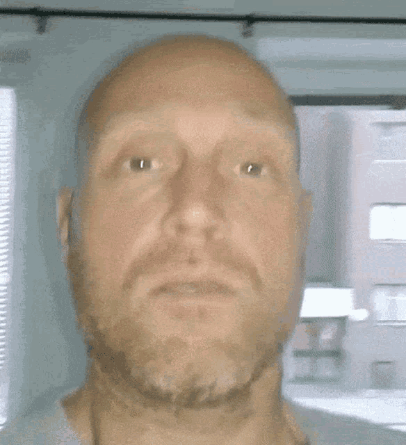 a bald man with a beard is making a funny face with his mouth open