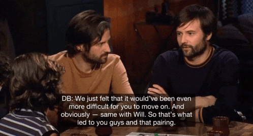 a group of men are sitting around a table and talking about a game