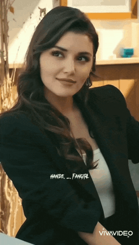a woman is wearing a black jacket and a white tank top ..