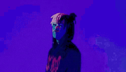 a man in a black hoodie is standing in front of a blue background .