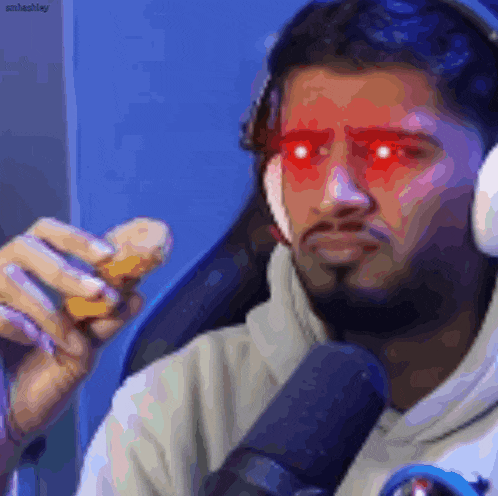 a man wearing headphones and red eyes is holding a sandwich in front of a microphone