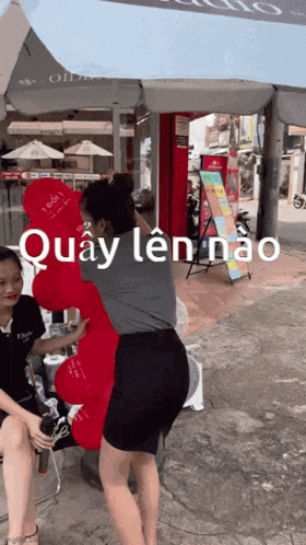 a woman is holding a red teddy bear that says quay len nao on the bottom