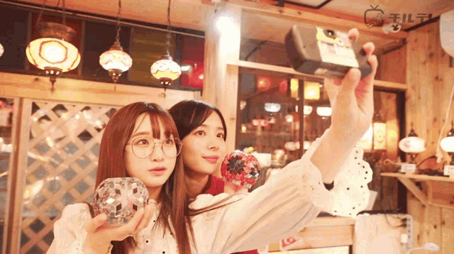 two women are taking a selfie in a room with a sign that says lg on it