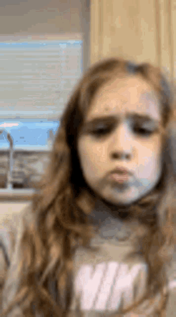 a little girl with long hair is making a funny face .