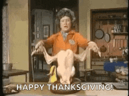 a woman is holding a turkey on a table and says happy thanksgiving .