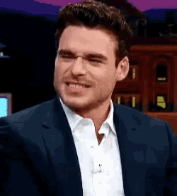 a man in a suit and white shirt is smiling and making a face .