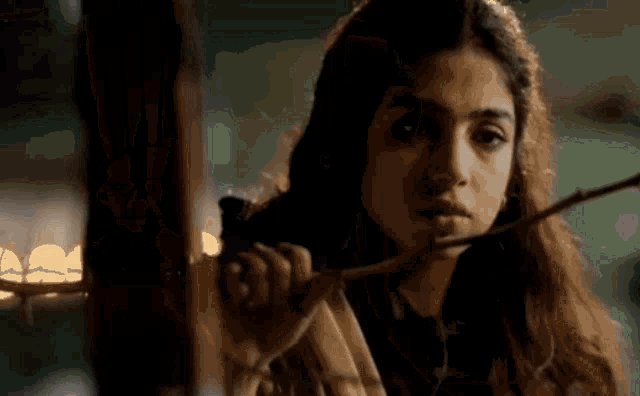 a woman with long hair is holding a stick in her hand .