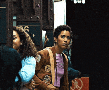 a woman wearing a brown jacket and a purple shirt that says " aventura " on it