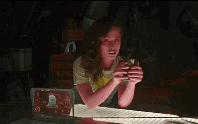 a woman sitting at a table looking at a screen that says ' a ' on it