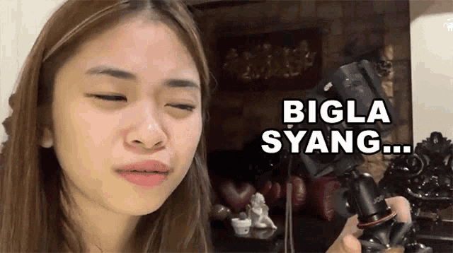 a woman is holding a camera with the words bigla syang written on the bottom
