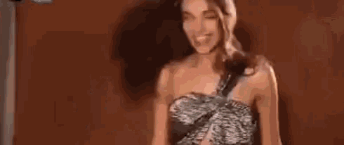 a woman in a strapless dress is standing in front of a sign that says ' a n ' on it .