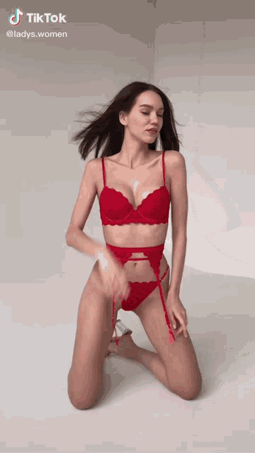a woman in red lingerie is kneeling down on the floor .