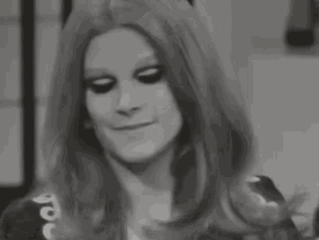a black and white photo of a woman with long red hair covering her nose with her hand .