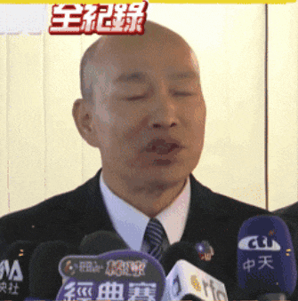 a man in a suit and tie is speaking into a microphone with chinese characters on it
