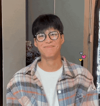 a young man wearing glasses and a plaid shirt smiles for the camera .