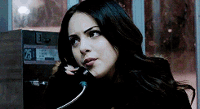 a woman is talking on a pay phone with the number 25 on it .