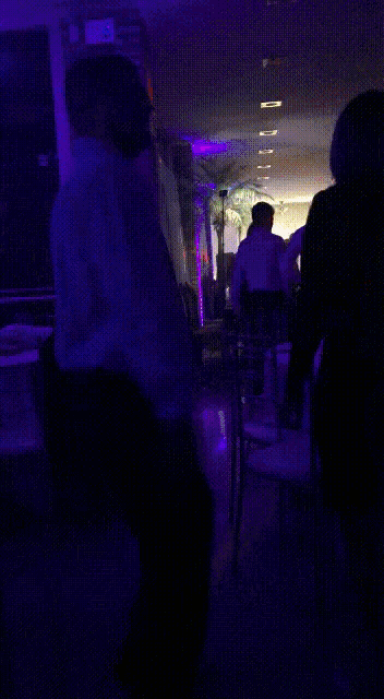 a man is dancing in a dark room with green lights behind him