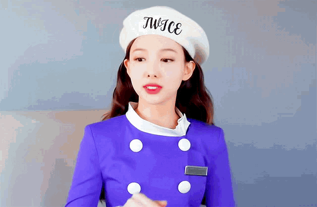 a woman wearing a purple jacket and a white hat with the word twice on it