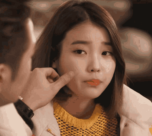 a woman wearing a yellow sweater is being touched by a man