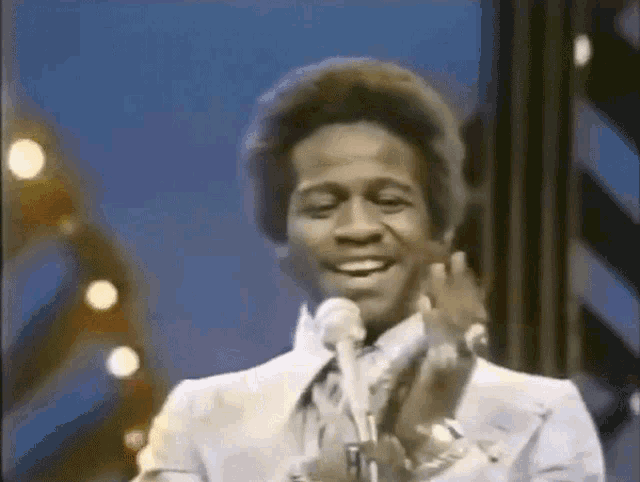 a man in a suit and tie is singing into a microphone on a stage .