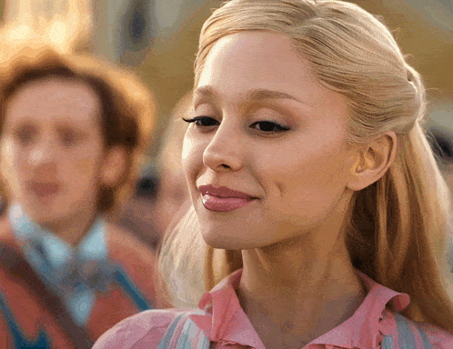 a woman in a pink shirt is smiling and looking at the camera