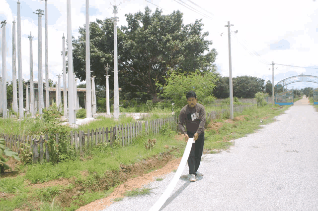 a man wearing a shirt that says ' nc ' on it is standing on a gravel road