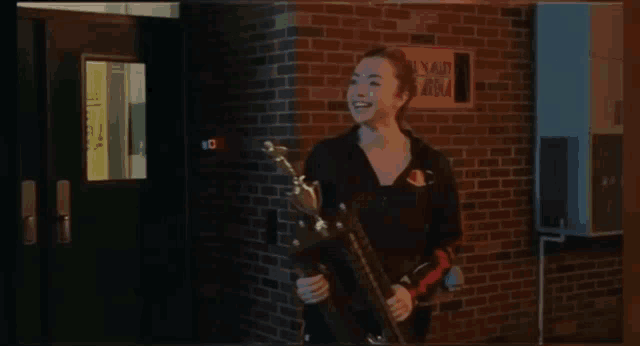 a woman is holding a trophy in front of a brick building with a sign that says no smoking