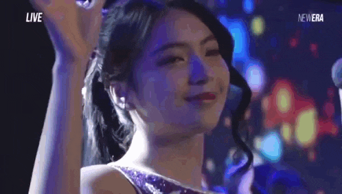 a woman in a purple dress is smiling and looking at the camera in a dark room .