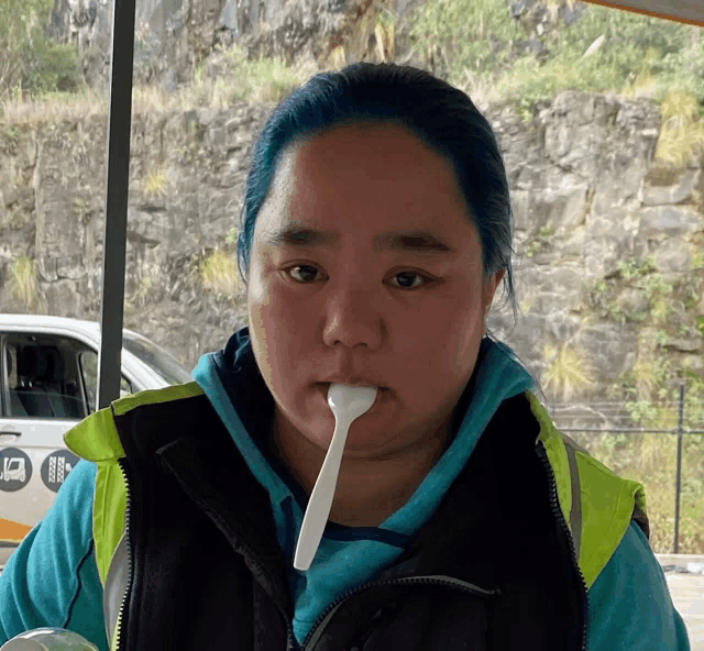 a woman with blue hair is eating something with a spoon