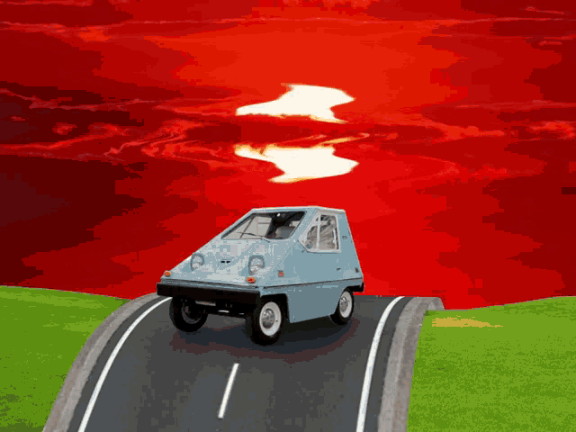 a small blue car is driving down a road in front of a red sky