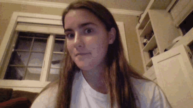 a woman in a white shirt looks at the camera