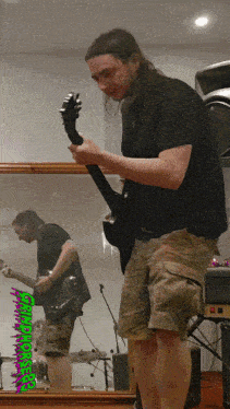 a man playing a guitar in front of a mirror with a picture of a man playing a guitar on the bottom of the image