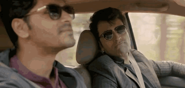 a man wearing sunglasses is sitting in the back seat of a car with another man