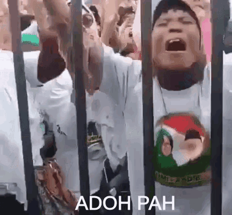 a group of people are standing behind a fence with the words adoh pah written on the bottom .