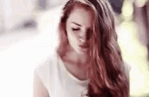the woman is wearing a white shirt and has long red hair .