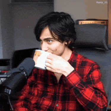a man wearing a plaid shirt is drinking from a cup with the name mary_t3 on the bottom