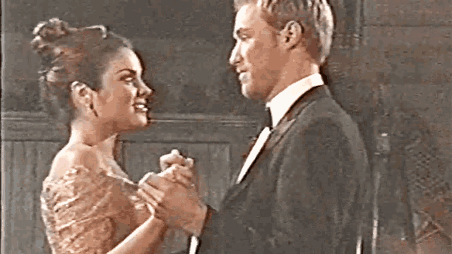 a man in a suit and a woman in a dress are dancing