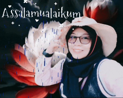 a woman wearing glasses and a hat is smiling in front of a flower and the words assalamualaikum