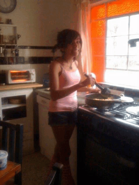 a woman in a pink tank top is preparing food on a stove