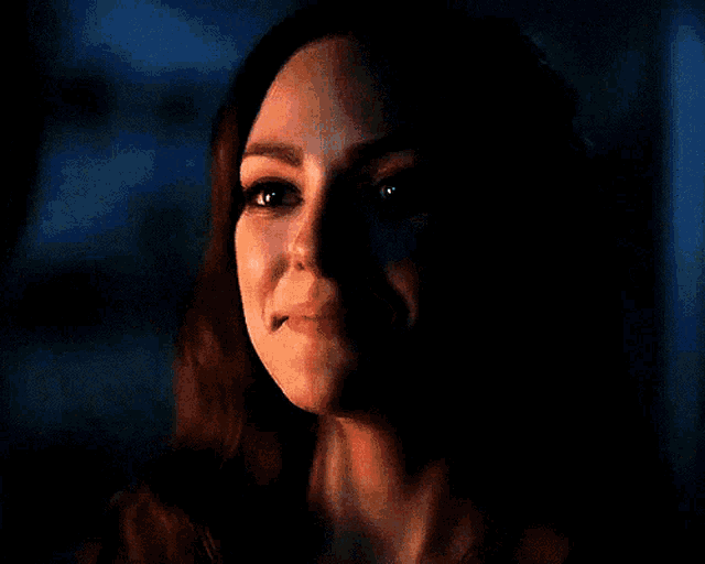 a close up of a woman 's face smiling in a dark room