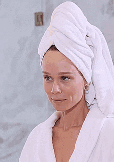 a woman with a towel wrapped around her head looks at the camera