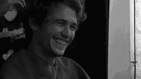 a black and white photo of a man smiling in a chair .
