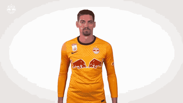 a man wearing a yellow jersey with red bulls on the front