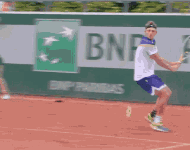 a tennis player is swinging a tennis racket in front of a bnp banner