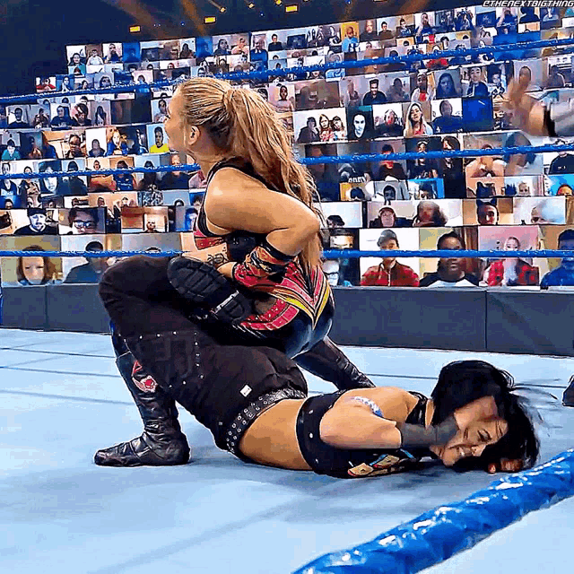 two women are wrestling in a wrestling ring with a crowd watching