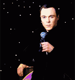 a man in a black shirt is holding a microphone in front of a podium with a purple star on it