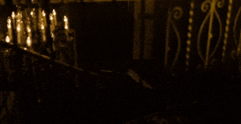 a silhouette of a man standing in a dark room with candles behind him