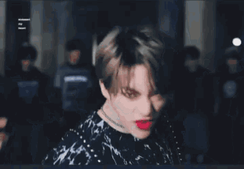 a young man with red lipstick on his lips is standing in front of a group of people .