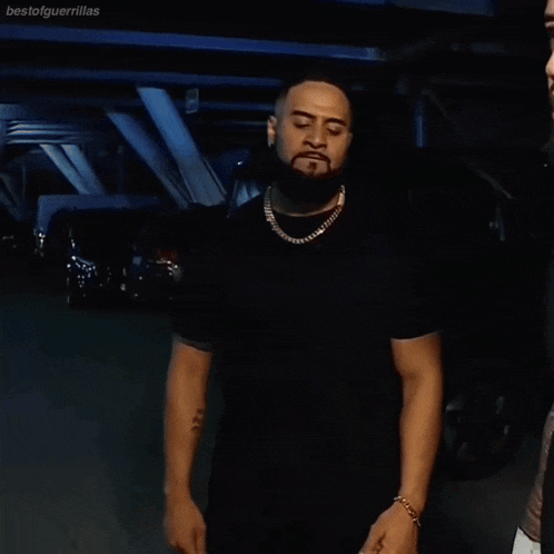 a man with a beard holds his hands to his head while talking to another man