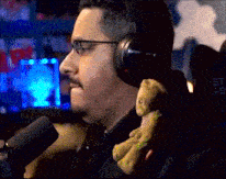 a man wearing headphones is holding a stuffed animal in front of a microphone